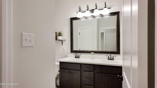 bathroom with a sink, toilet, and double vanity