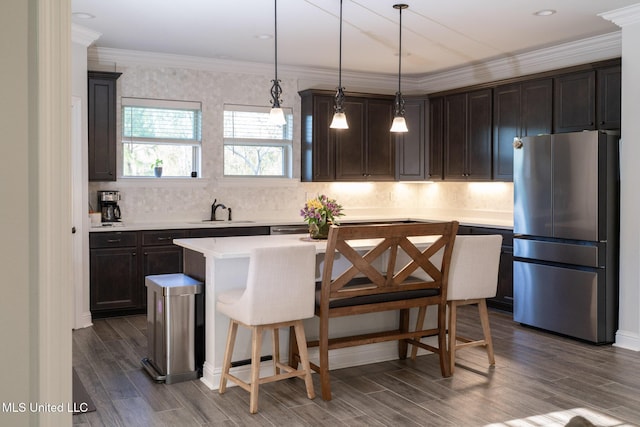 kitchen with light countertops, freestanding refrigerator, wood tiled floor, a sink, and dark brown cabinets