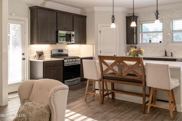 kitchen featuring stainless steel appliances, dark brown cabinets, a sink, and light countertops