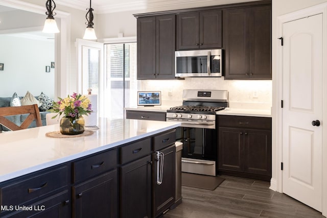 kitchen featuring stainless steel appliances, dark wood-type flooring, light countertops, ornamental molding, and pendant lighting