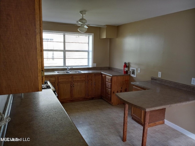 kitchen featuring sink, ceiling fan, kitchen peninsula, and gas range gas stove