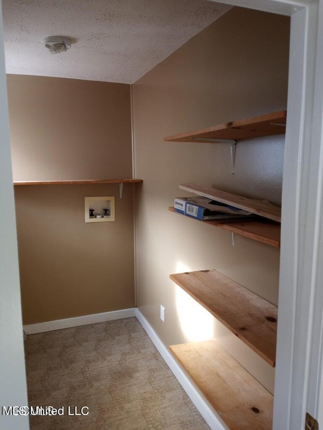 clothes washing area featuring washer hookup, a textured ceiling, and light colored carpet