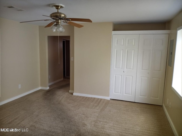 unfurnished bedroom featuring a closet, ceiling fan, electric panel, and light colored carpet