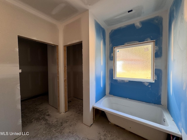 bathroom with a tub to relax in and concrete flooring