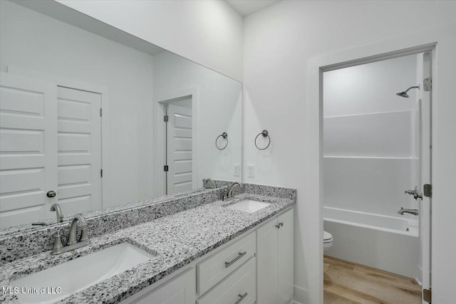 full bathroom featuring hardwood / wood-style floors, vanity, toilet, and shower / washtub combination