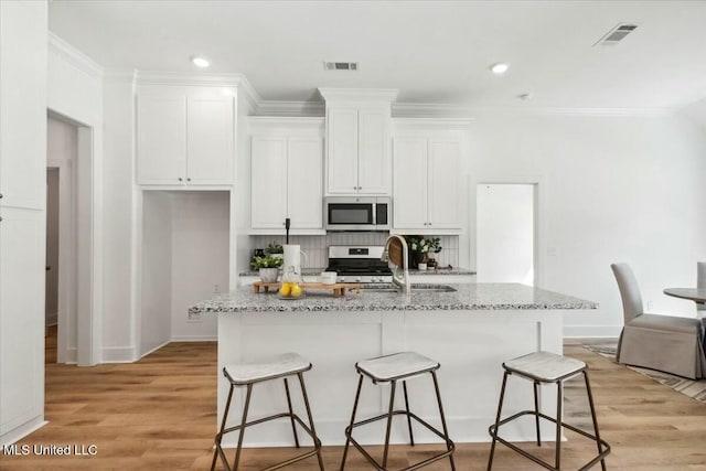 213 Dolly Ln, Magee, MS 39111 - kitchen with appliances with stainless steel finishes, a sink, a breakfast bar, white cabinets, and crown molding