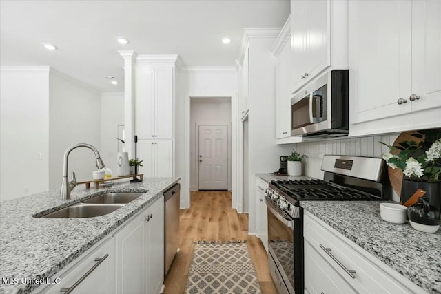 213 Dolly Ln, Magee, MS 39111 - kitchen featuring appliances with stainless steel finishes, a sink, ornamental molding, white cabinetry, and light wood-type flooring