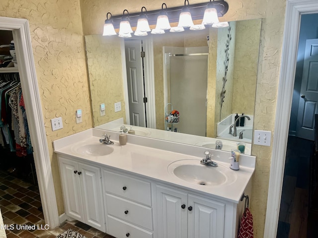 1024 Riverchase N Dr, Brandon, MS 39047 - bathroom featuring a shower stall, double vanity, a spacious closet, a textured wall, and brick patterned flooring