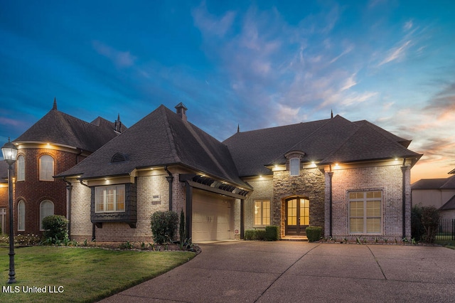 french provincial home with a garage and a lawn