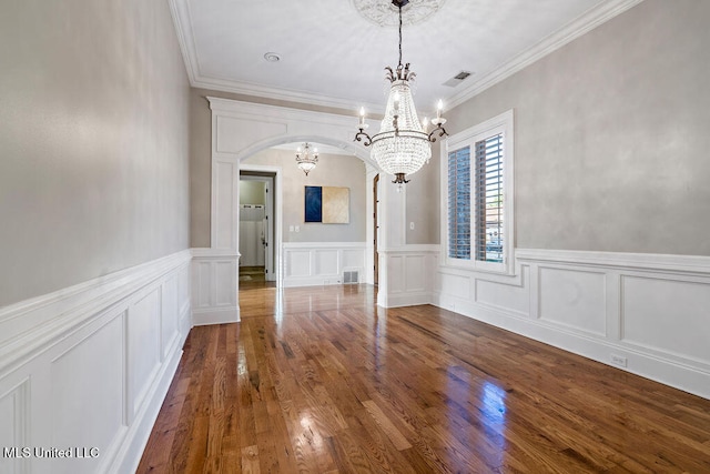 unfurnished dining area featuring crown molding, a notable chandelier, and hardwood / wood-style flooring