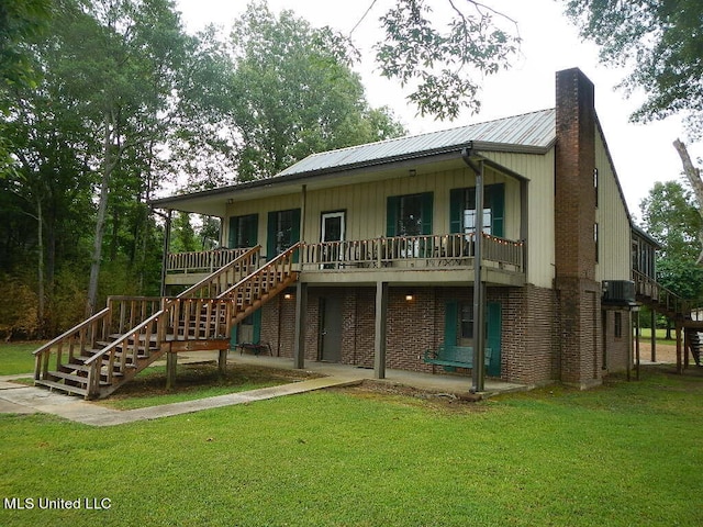 rear view of house with cooling unit, a chimney, metal roof, stairway, and a yard