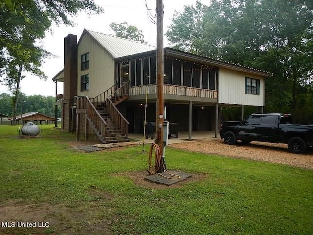 rear view of property featuring a yard and a sunroom