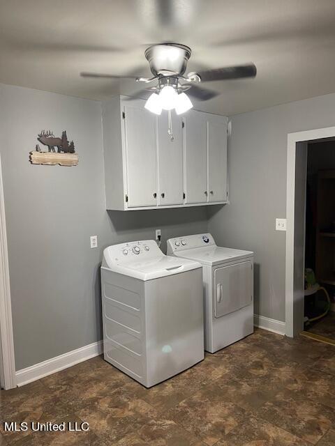 clothes washing area with washing machine and dryer, stone finish flooring, ceiling fan, baseboards, and cabinet space