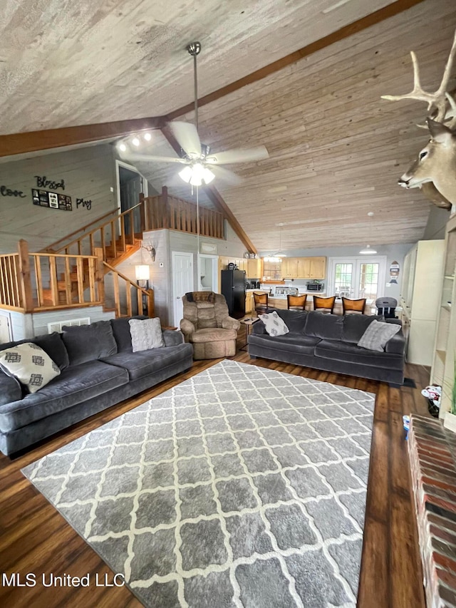 living room with wooden walls, lofted ceiling with beams, hardwood / wood-style flooring, and ceiling fan