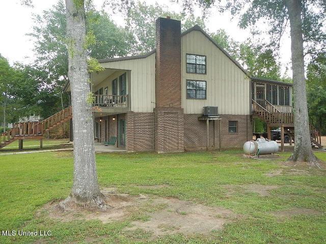 rear view of property with a deck, cooling unit, a lawn, and a sunroom