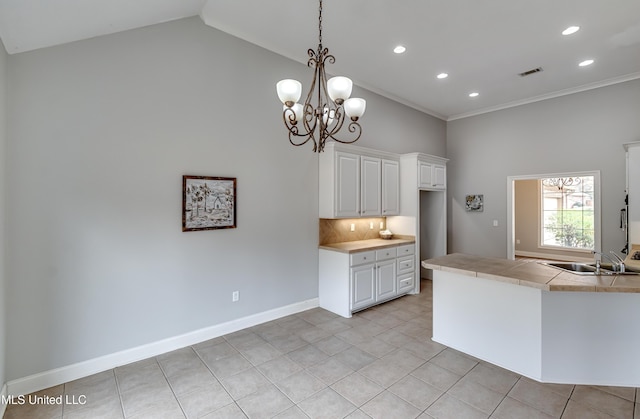 kitchen with light tile patterned flooring, white cabinetry, sink, decorative backsplash, and hanging light fixtures