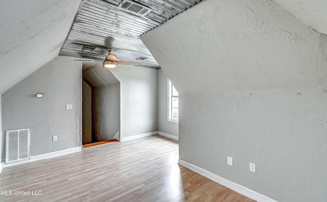 bonus room featuring lofted ceiling, a textured ceiling, and light hardwood / wood-style flooring