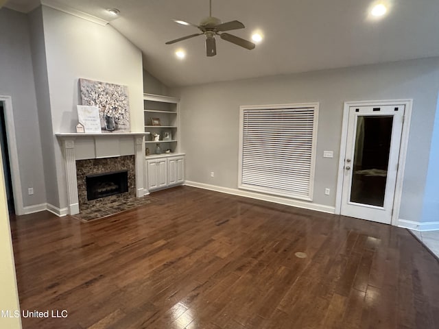 unfurnished living room with dark hardwood / wood-style flooring, vaulted ceiling, ceiling fan, and a high end fireplace