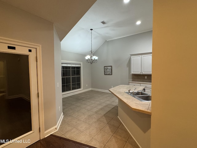 kitchen featuring vaulted ceiling, decorative light fixtures, white cabinetry, sink, and a notable chandelier