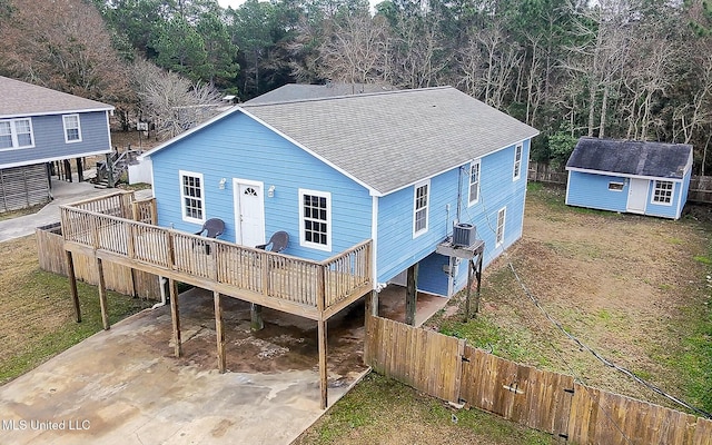 rear view of house featuring a wooden deck, central AC unit, a carport, and a storage unit