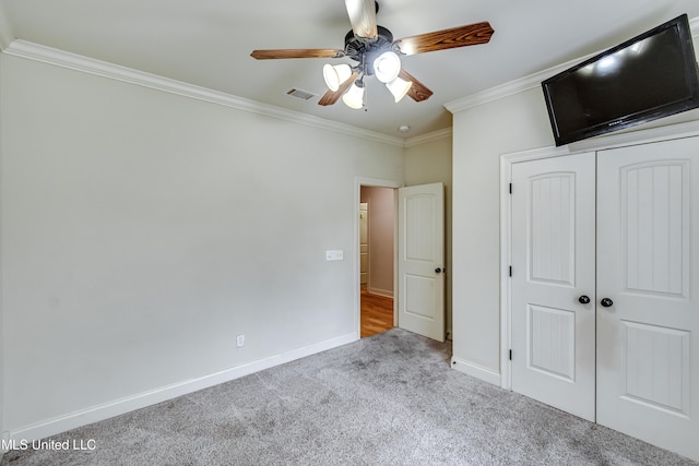 unfurnished bedroom featuring crown molding, ceiling fan, a closet, and light carpet