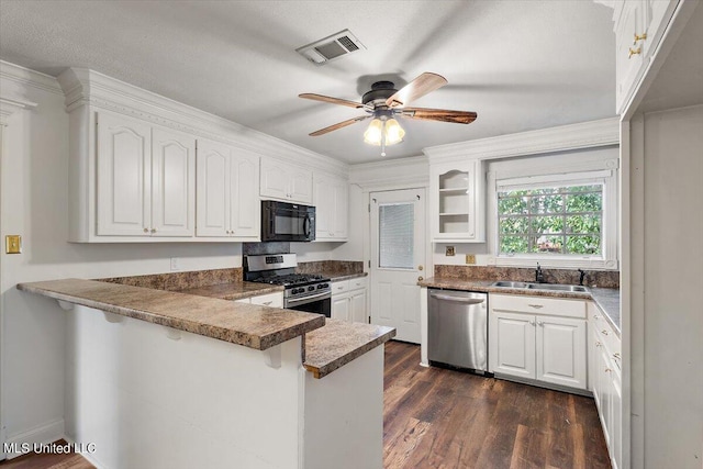 kitchen featuring kitchen peninsula, sink, white cabinetry, appliances with stainless steel finishes, and dark hardwood / wood-style flooring