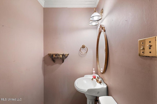 bathroom with toilet, ornamental molding, and sink