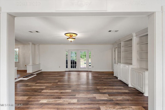 unfurnished living room featuring french doors, dark wood-type flooring, and ornate columns