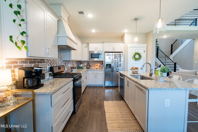 kitchen featuring dark wood-type flooring, sink, decorative light fixtures, white cabinetry, and appliances with stainless steel finishes