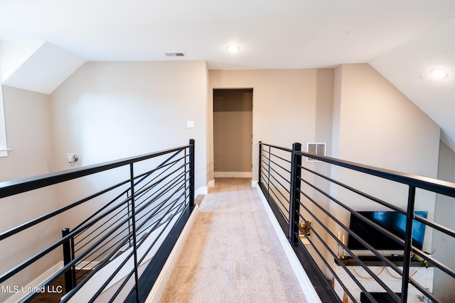 hall featuring vaulted ceiling and light colored carpet