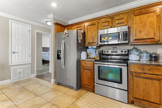 kitchen featuring visible vents, ornamental molding, stainless steel appliances, brown cabinetry, and light tile patterned floors