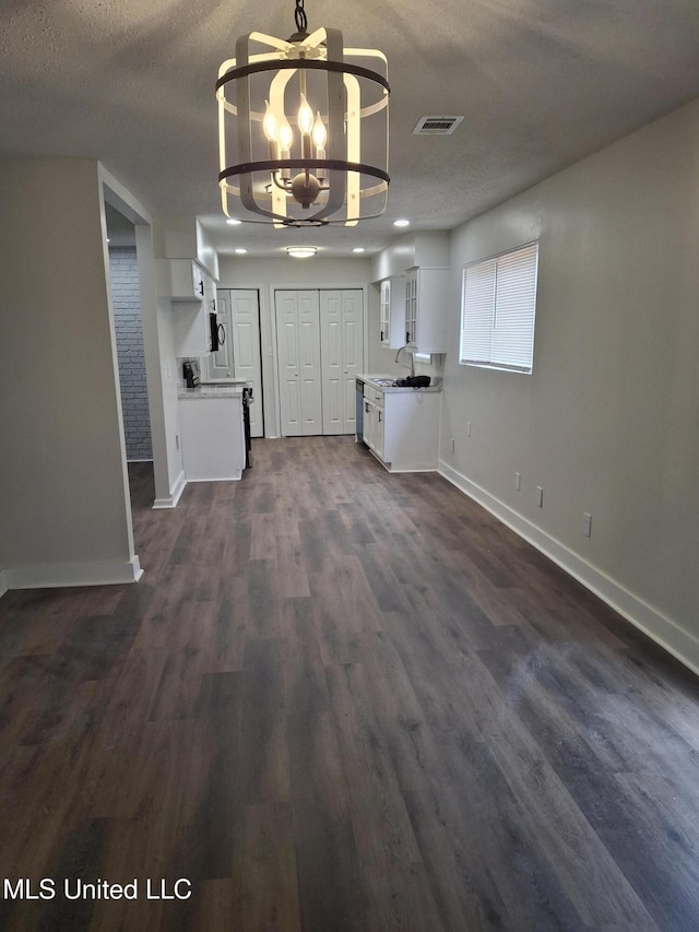 unfurnished living room featuring a notable chandelier, sink, dark hardwood / wood-style floors, and a textured ceiling