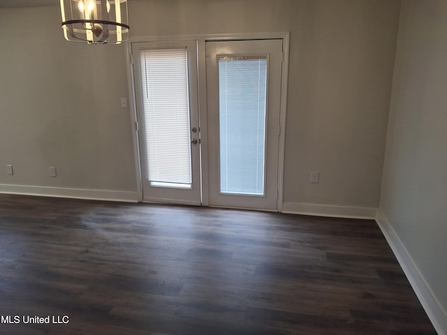 spare room featuring dark hardwood / wood-style flooring, french doors, and a notable chandelier