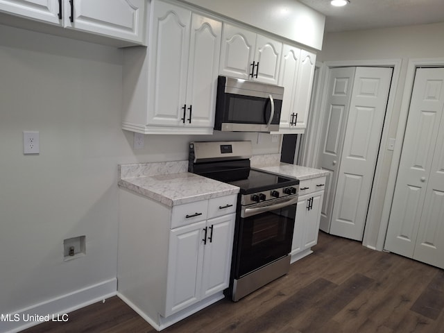 kitchen with appliances with stainless steel finishes, dark hardwood / wood-style flooring, and white cabinets