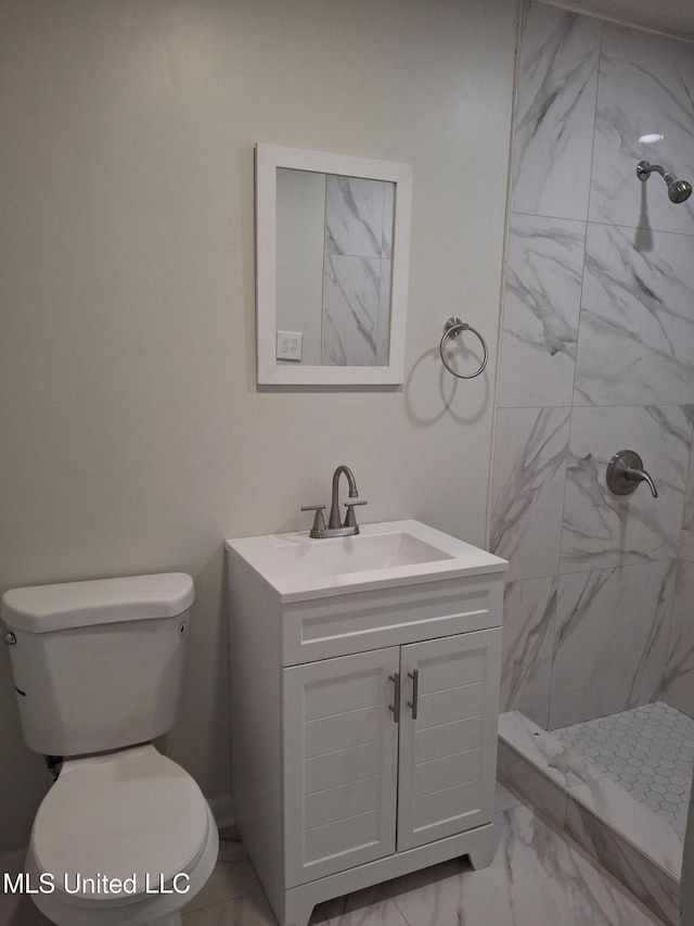 bathroom featuring a tile shower, vanity, and toilet