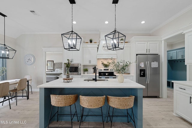 kitchen featuring a kitchen bar, custom exhaust hood, decorative light fixtures, appliances with stainless steel finishes, and a kitchen island with sink