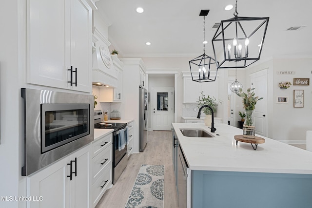 kitchen featuring an island with sink, appliances with stainless steel finishes, sink, and white cabinets