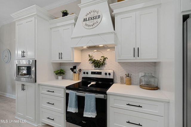 kitchen with range with electric stovetop, stainless steel microwave, white cabinetry, backsplash, and custom exhaust hood