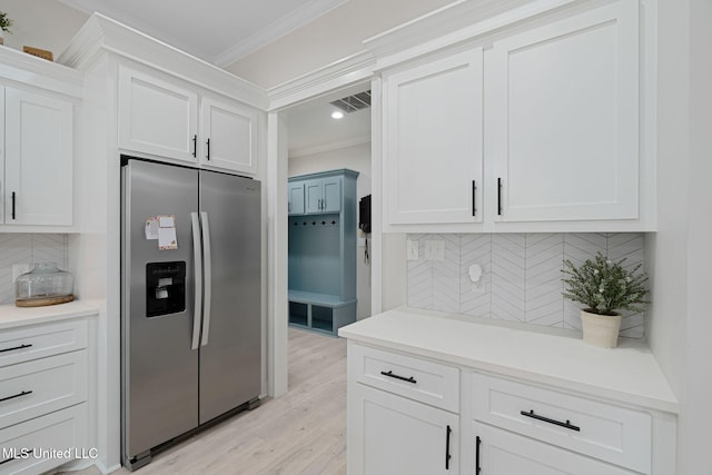 kitchen with crown molding, stainless steel refrigerator with ice dispenser, white cabinets, decorative backsplash, and light wood-type flooring