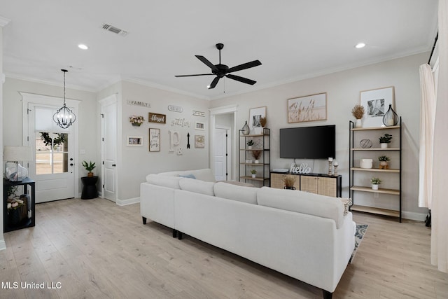 living room featuring ceiling fan with notable chandelier, ornamental molding, and light wood-type flooring