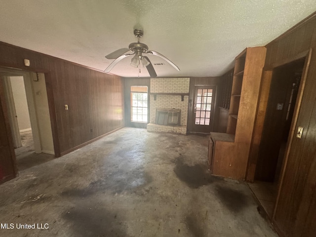 2318 Breckinridge Rd, Jackson, MS 39204 - unfurnished living room featuring wood walls, a ceiling fan, concrete floors, and a fireplace