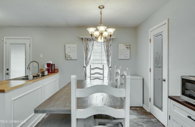 dining room with an inviting chandelier, sink, and dark wood-type flooring