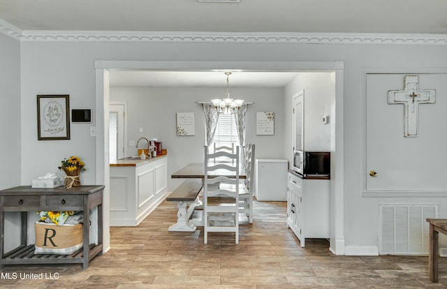 dining room featuring sink, a notable chandelier, and light hardwood / wood-style flooring