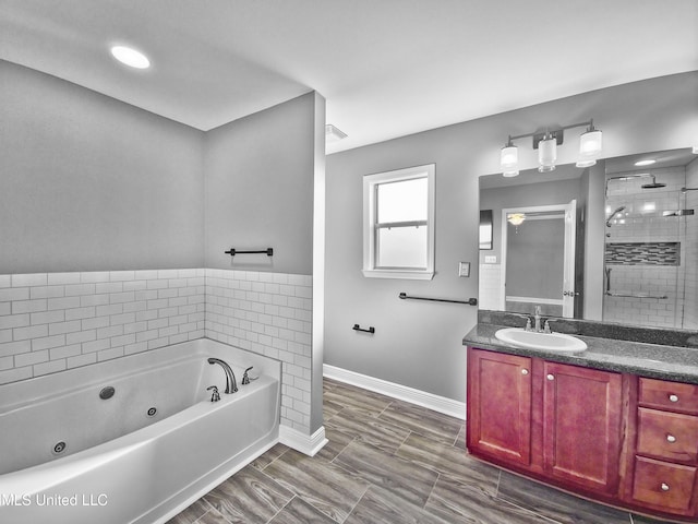 bathroom with a whirlpool tub, baseboards, tiled shower, and vanity