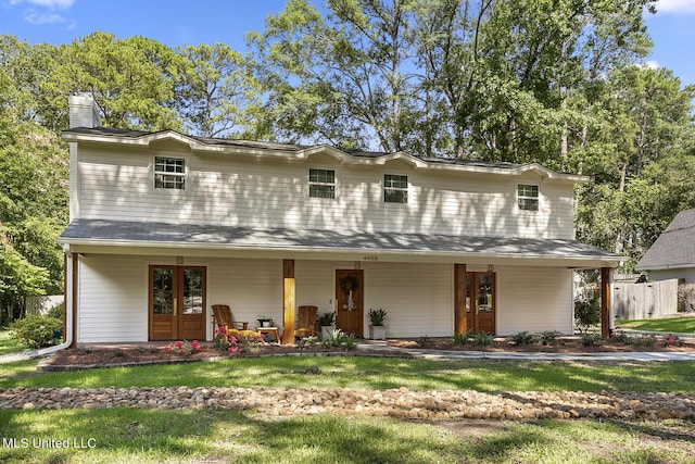 view of front of home featuring covered porch, french doors, a chimney, and fence