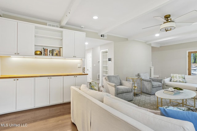 living area with recessed lighting, visible vents, beamed ceiling, and light wood-style flooring