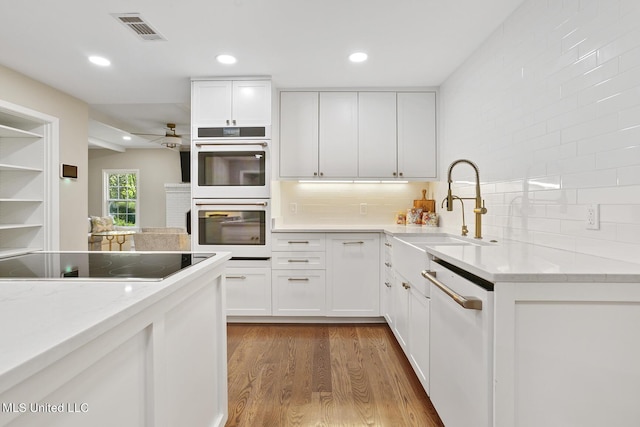 kitchen with visible vents, light wood-style flooring, white cabinets, a sink, and white appliances