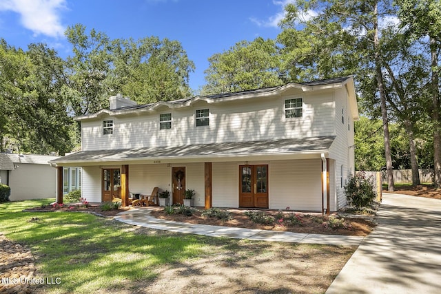 view of front of property with a porch, fence, a chimney, and a front lawn