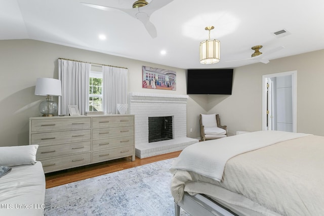 bedroom featuring visible vents, wood finished floors, vaulted ceiling, a fireplace, and recessed lighting