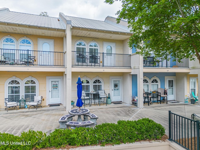 back of property with metal roof, a balcony, and stucco siding